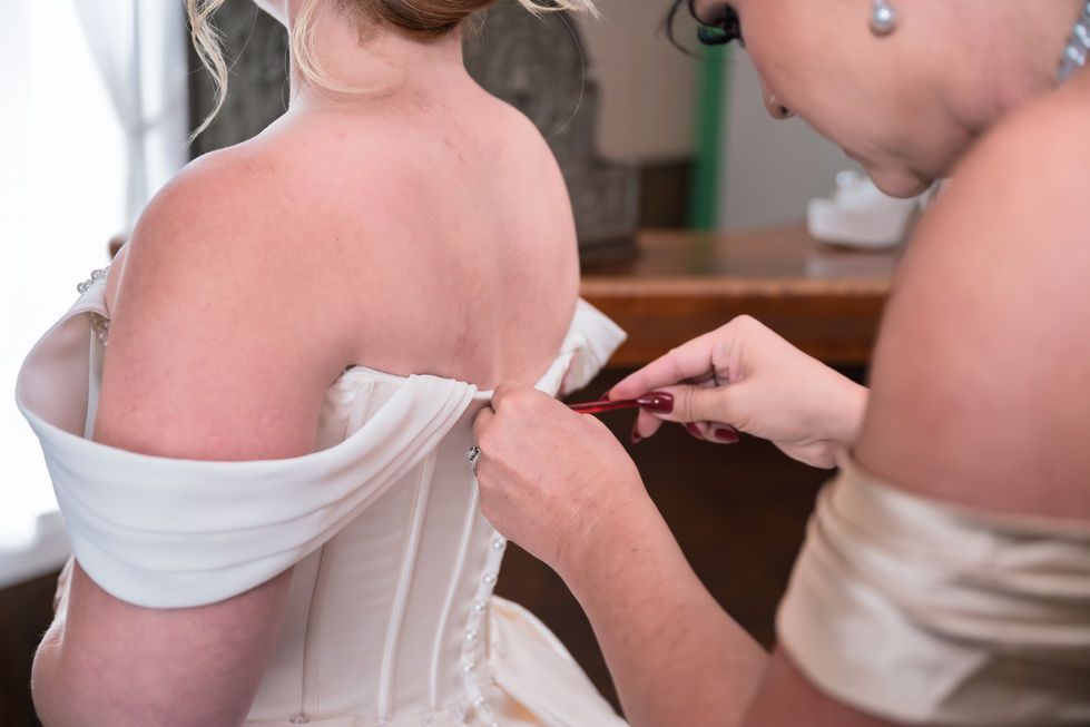 Bride's dress being adjusted by another person.