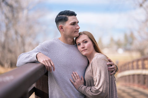 a man and a woman are posing for a picture and the woman is wearing an engagement ring
