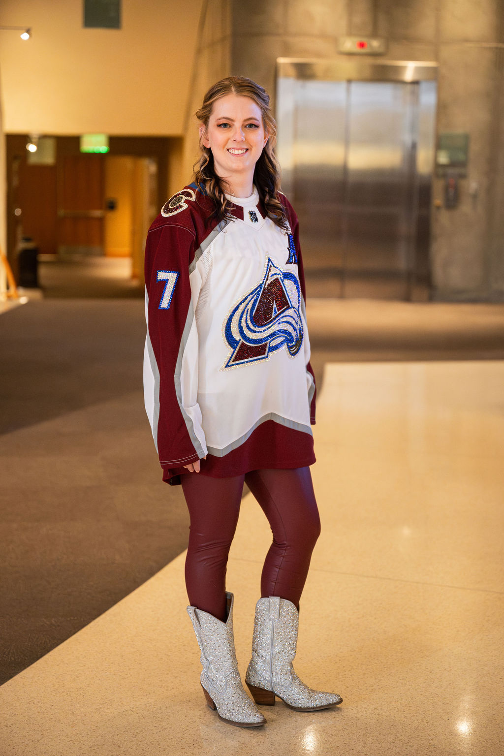 Person wearing a hockey jersey and boots indoors.