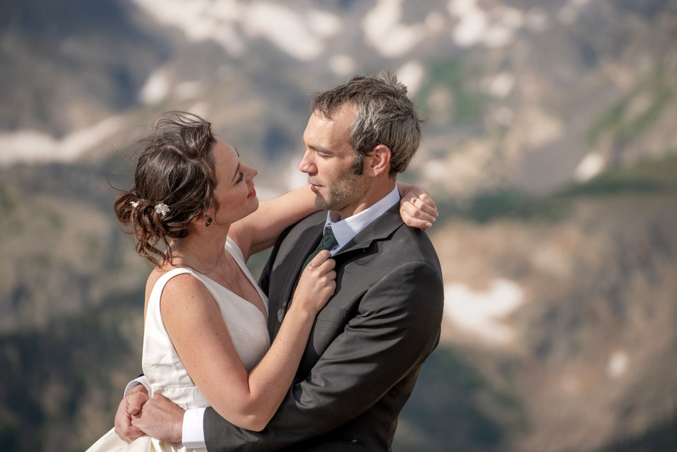 a bride and groom looking at each other with mountains in the background