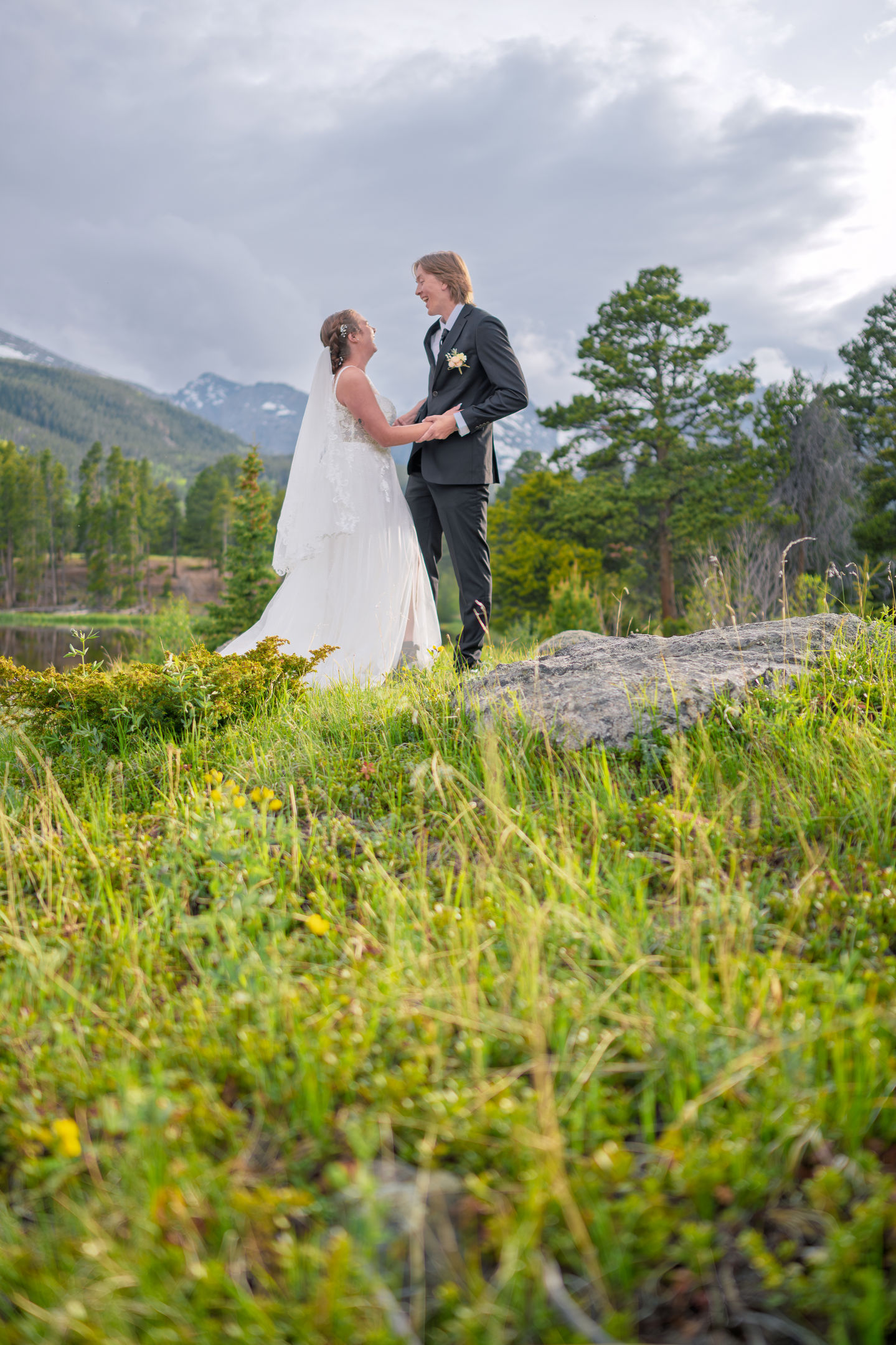 a bride and groom holding hands in a field with mountains in the background