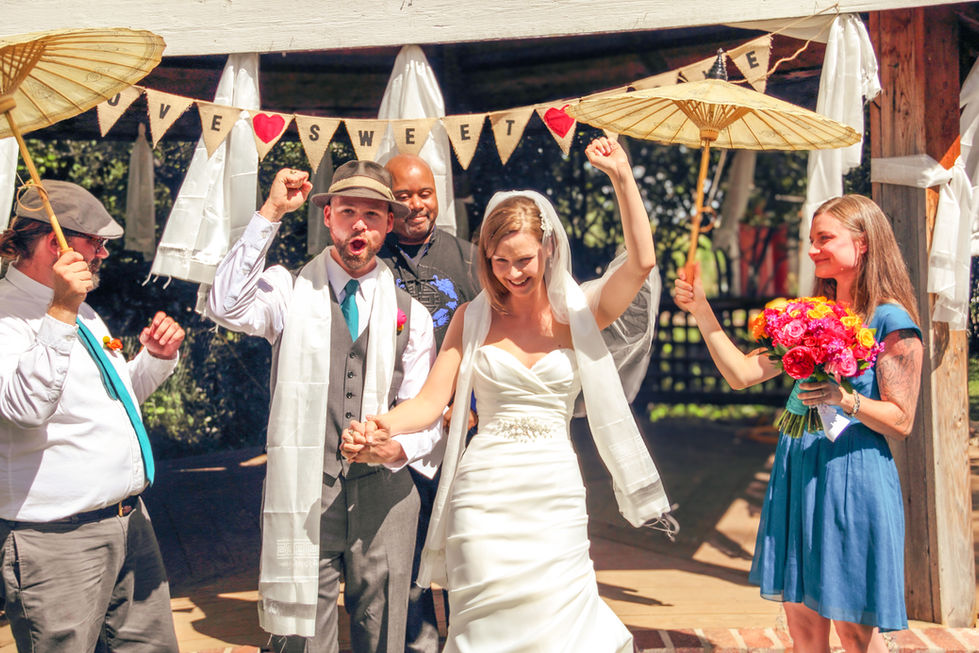 a bride and groom are celebrating their wedding under a banner that says " sweet "