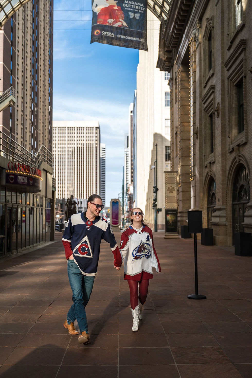 Couple walking in city wearing hockey jerseys.