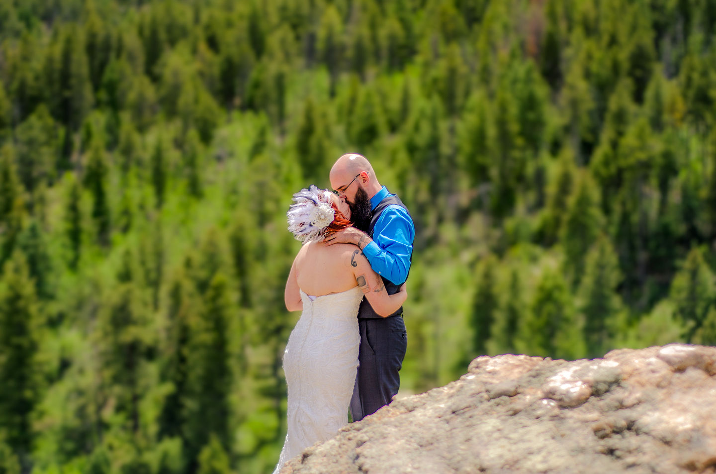 a man in a blue shirt kisses a woman in a white dress