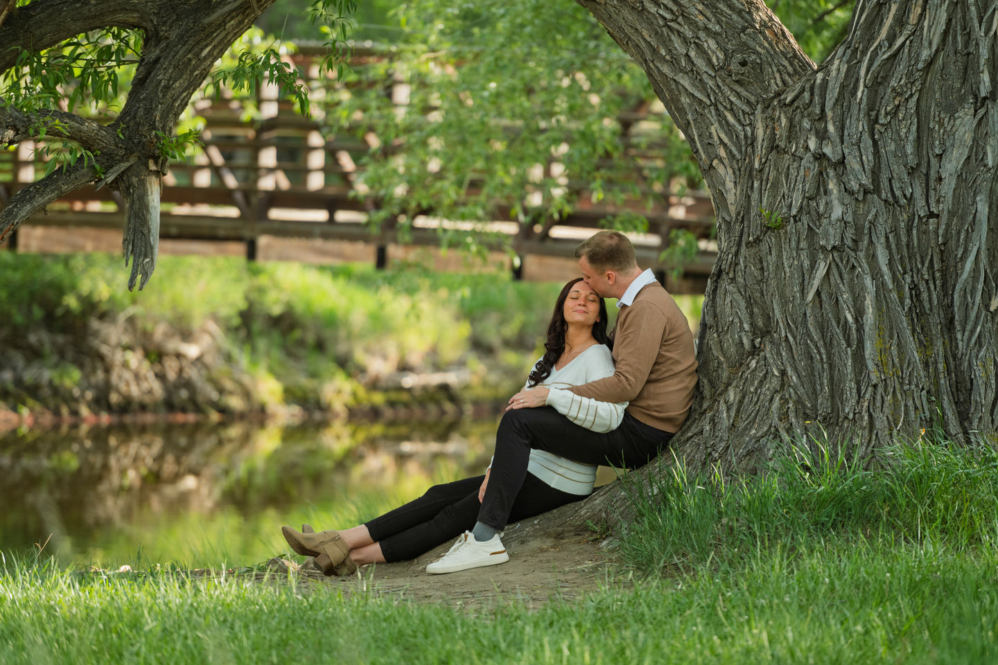 a man kisses a woman while sitting under a tree
