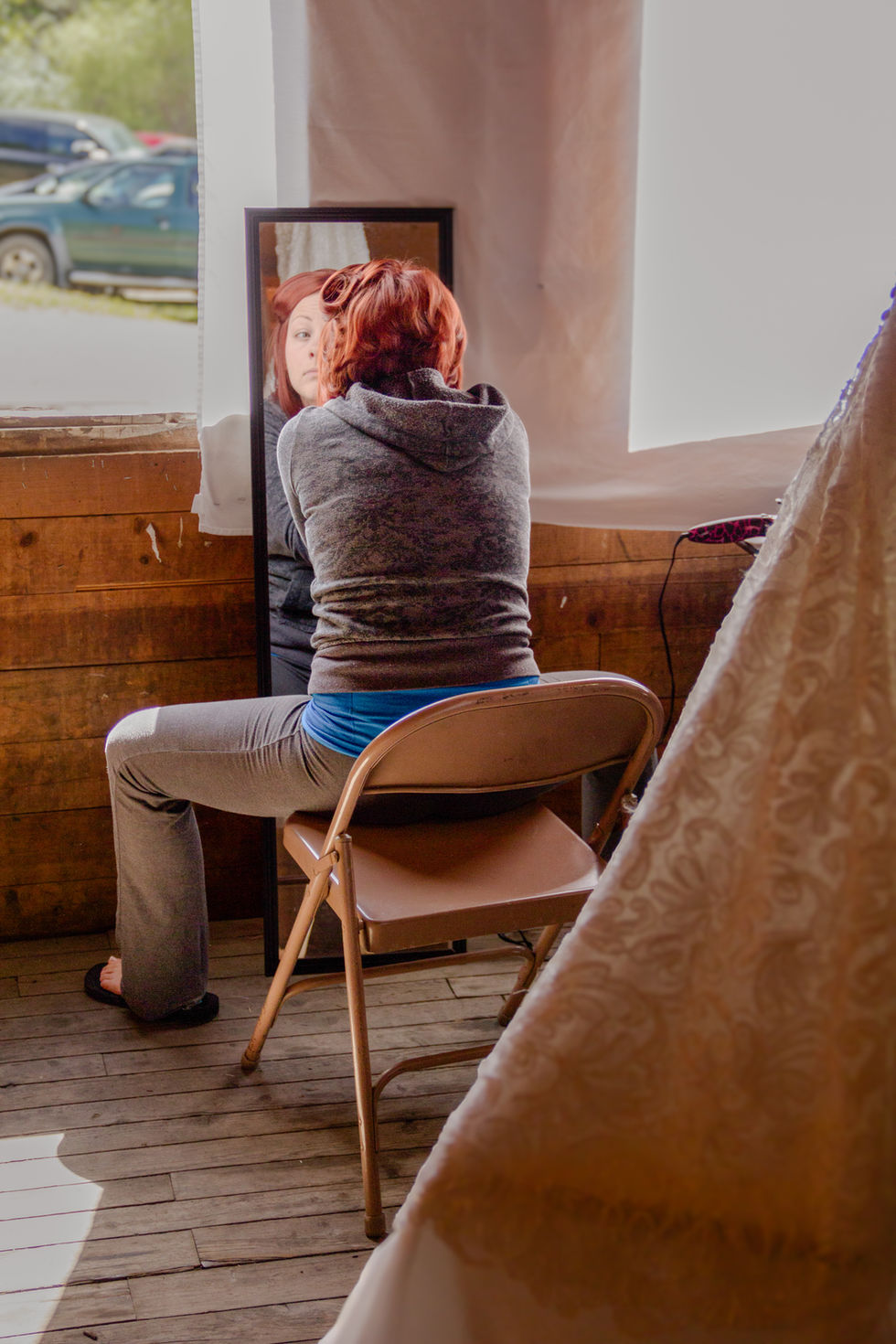 a woman sitting in a chair looking at herself in a mirror