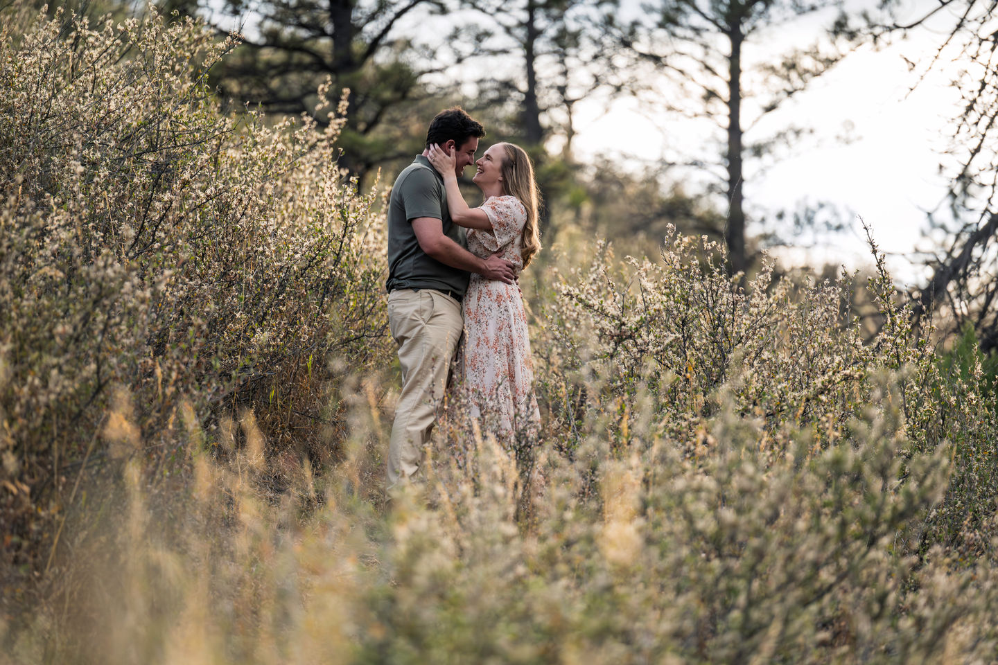 Couple embracing in a field with tall grass.