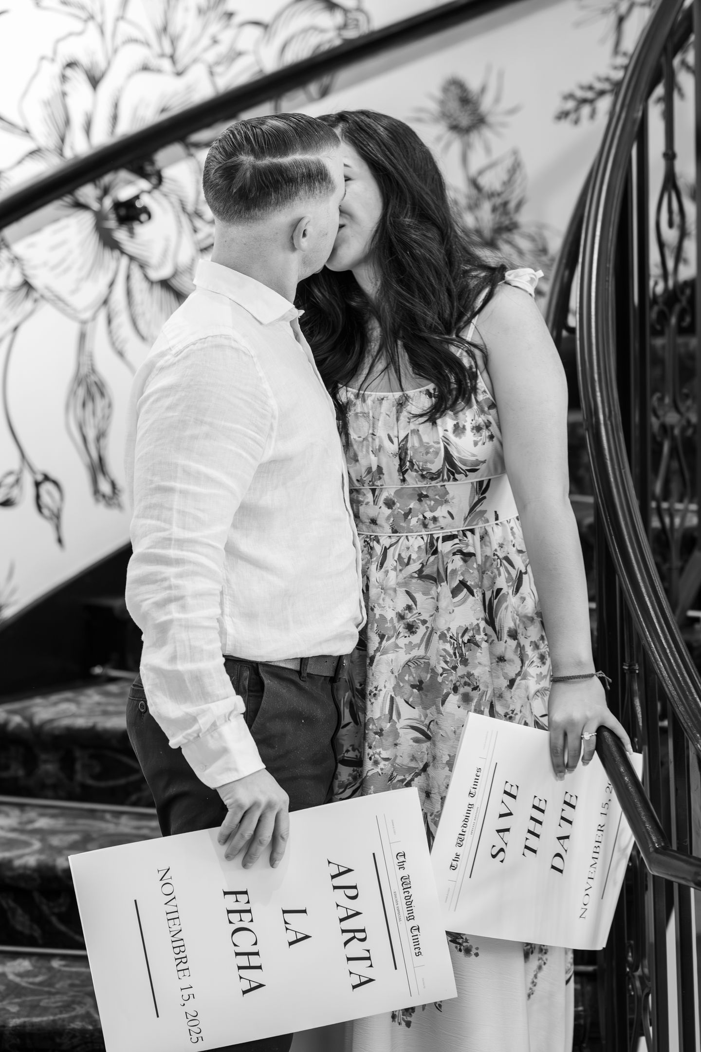 a man and woman kissing while holding save the date cards