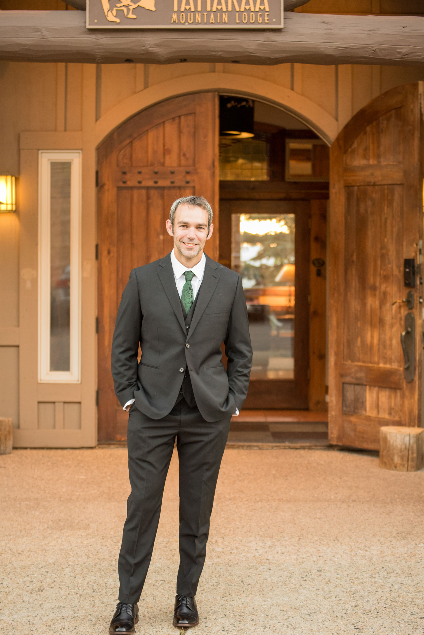 a man in a suit and tie stands in front of a wooden door