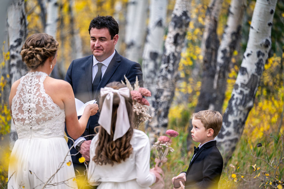 Bride and groom with children in forest ceremony.