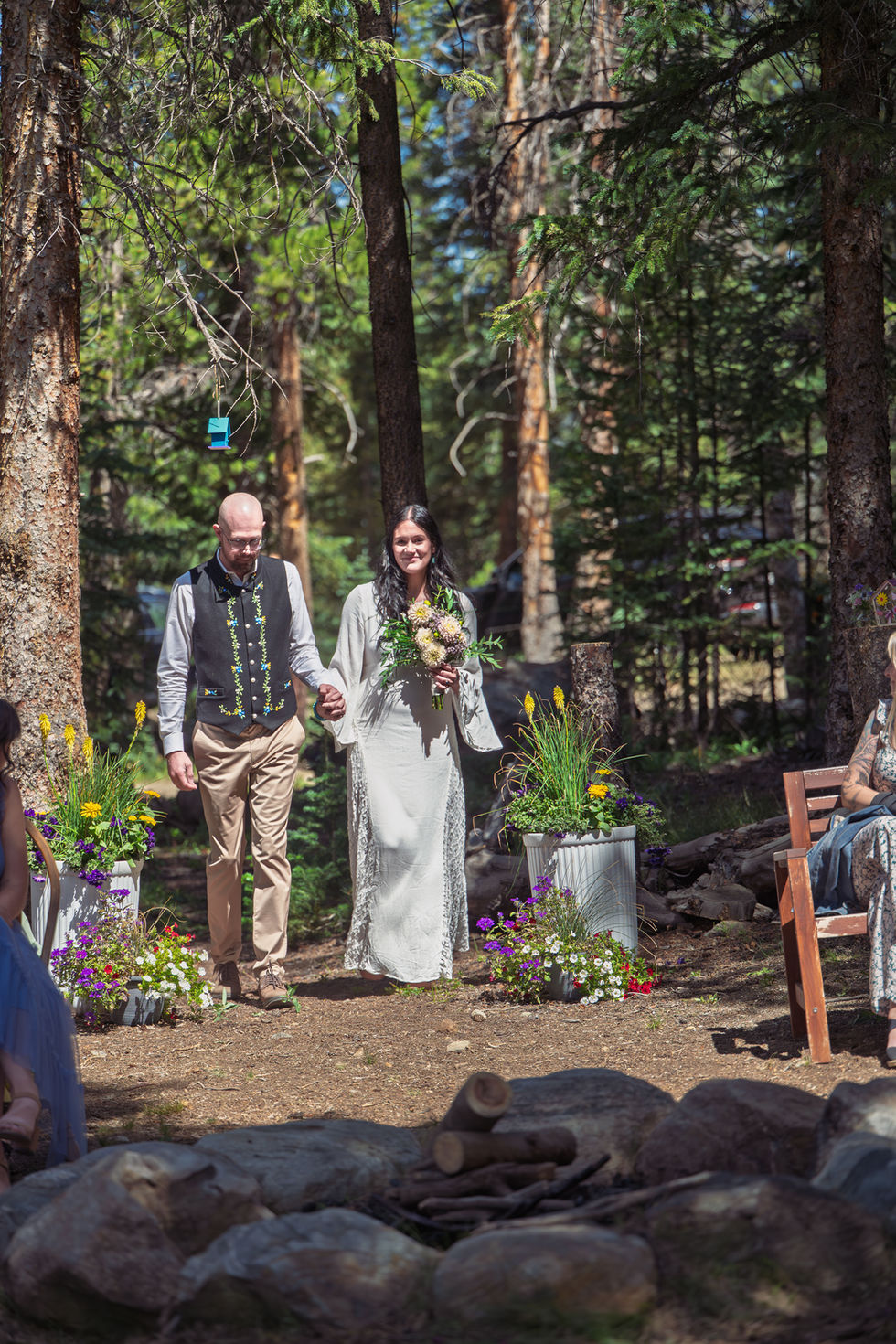 Bride and groom walking in forest wedding ceremony.