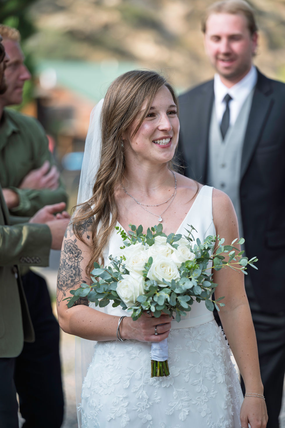 Bride holding bouquet, smiling at wedding ceremony.