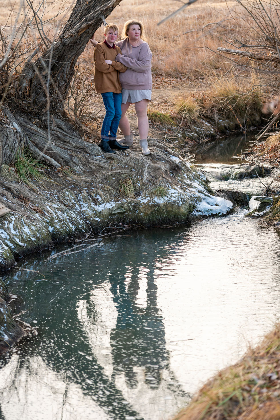 a couple standing next to a stream with their feet in the water