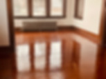 An image of an empty room with polished hardwood floors and a large window, creating a serene and spacious ambiance.