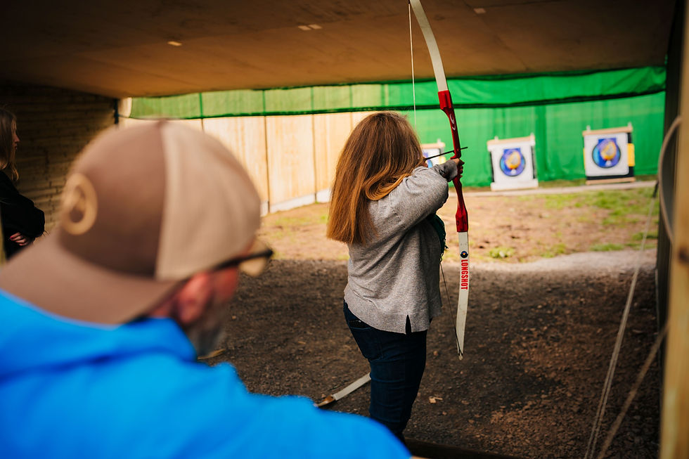 A woman pulls back the string of her bow as she aims at a target downrange at an activity centre near Churchill, Somerset.