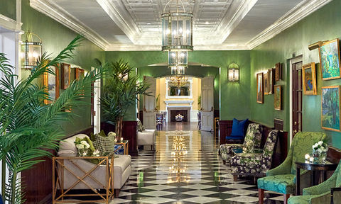 Stylish lounge area with floral armchairs and greenery in an elegant hallway with green walls