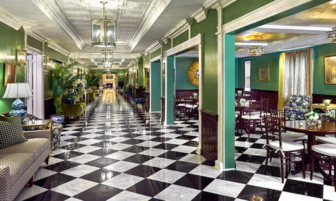 Sophisticated venue hallway with green walls, black-and-white checkered floors, and vintage-style furniture