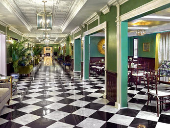 Sophisticated venue hallway with green walls, black-and-white checkered floors, and vintage-style furniture