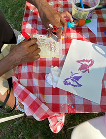 Hands drawing on paper on a red and white checkered tablecloth
