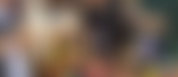 Four women standing around a table making popsicle dolls. 