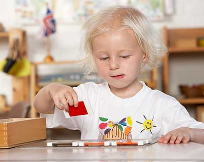 Fillette travaillant avec le matériel Montessori, la 2ème boîte de couleurs. L'école Montessori Bilingue Smiles'n Kids située dans le 92 à Issy-les-Moulineaux proche de Meudon applique la pédagogie Montessori.