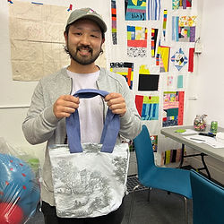 Student in a hat holding a newly finished tote bag.