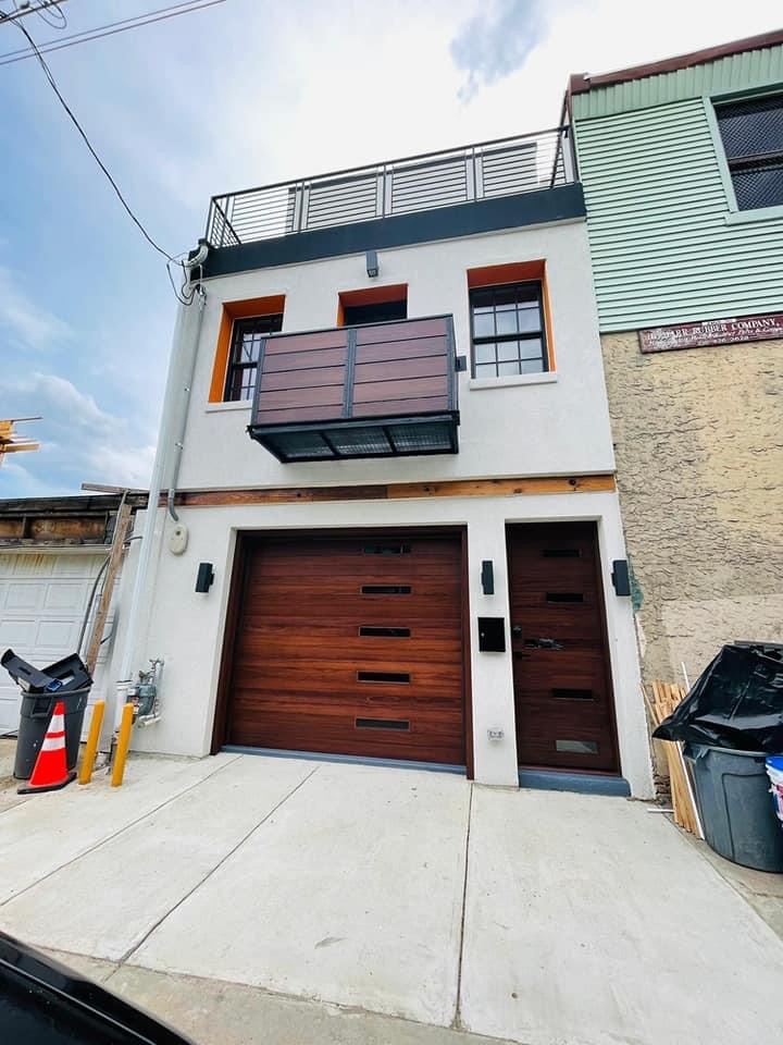 Distinctive rehabbed rowhome facade with garage and wood balcony in Kensington
