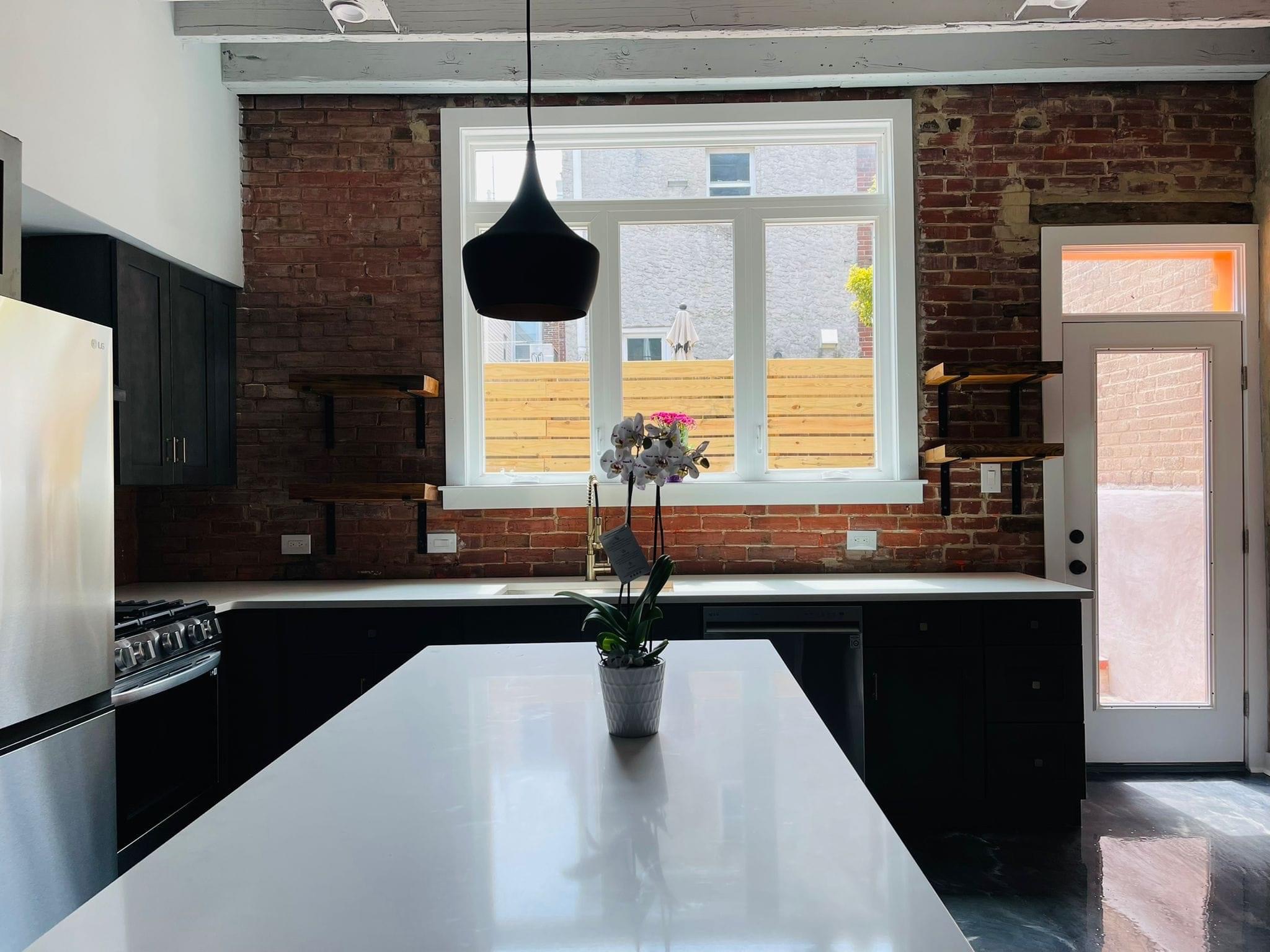 Custom kitchen with black cabinetry against exposed brick