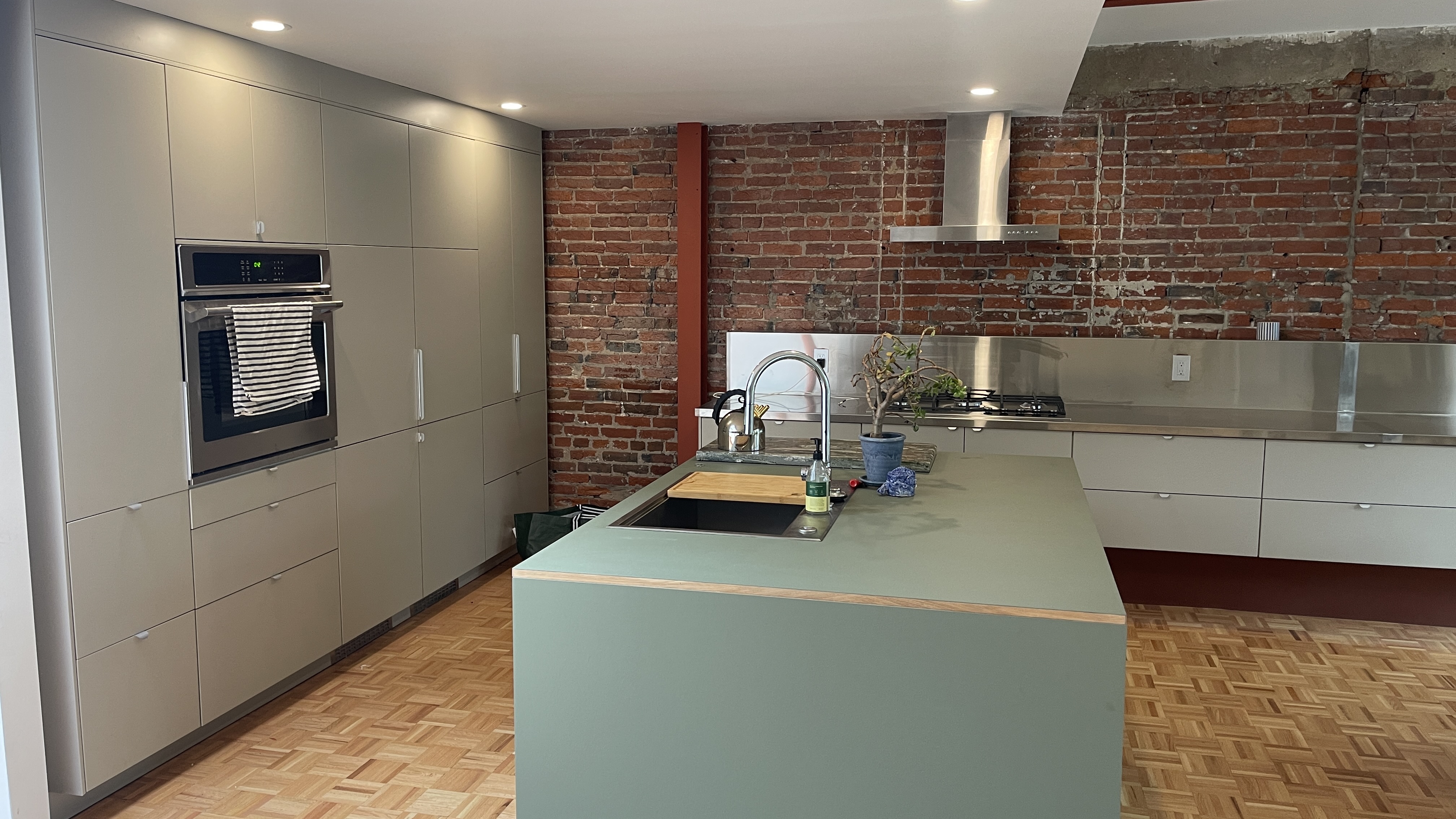 Green custom kitchen against original brick in the Queen Village rehab
