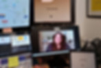 A woman on a video call displayed across multiple computer monitors during online training.