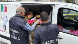 Guardia di Finanza durante controlli su gadget non conformi del Giro d’Italia 2026 tra Praia a Mare e Scalea