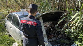 Carabinieri Forestali ispezionano un'area recintata a fondo naturale piena di rifiuti ingombranti, elettrodomestici e carcasse d'auto