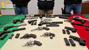 Militari Guardia di Finanza Reggio Calabria accanto ad armi sequestrate, mitragliatrici UZI e Skorpion