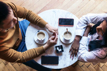 aerial-shot-of-a-cafeteria-table-where-two-people-drink-coffee-an-asian-man-and-a-latin-am