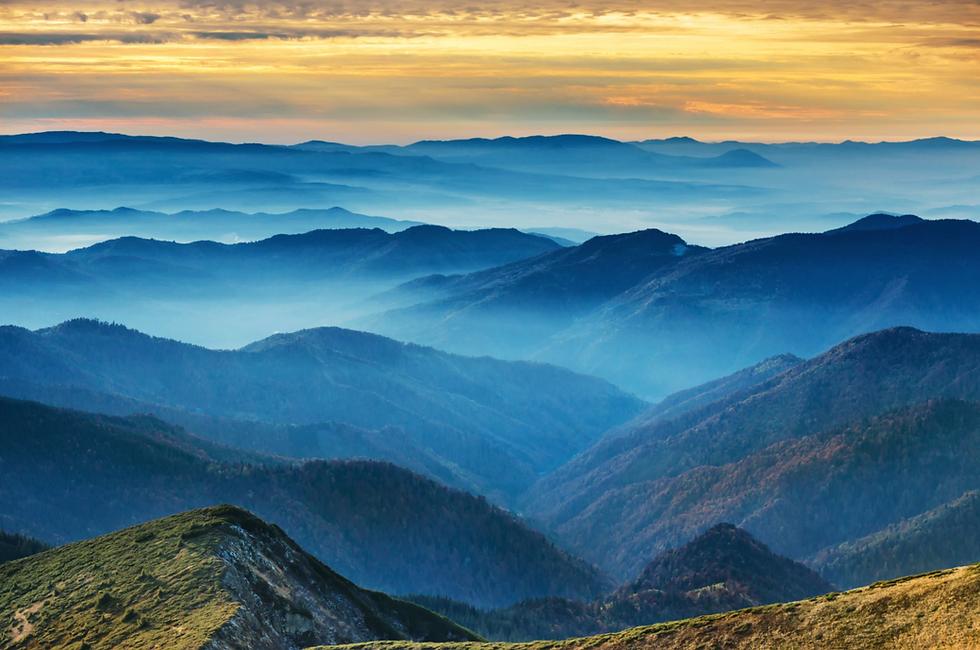 Mountain landscape with layered blue hills under a golden-yellow sky, creating a serene and tranquil atmosphere. No text visible.