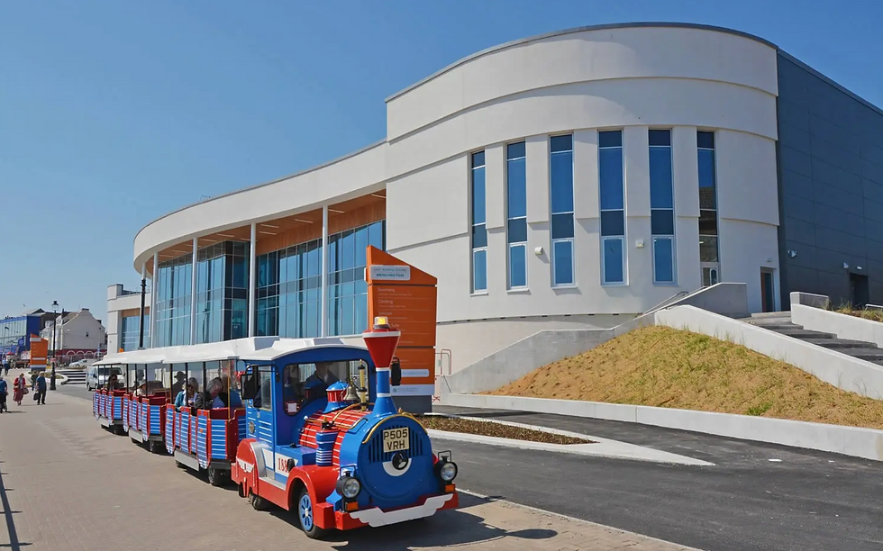 A bright scene outside Bridlington Leisure Centre near Bungalow Farm in Buckton, with the modern curved building and colourful land train on a sunny day by the Yorkshire coast.
