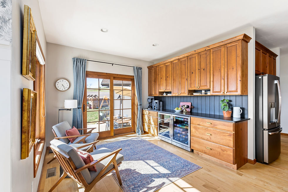 Charming corner with built-in beverage bar, glass-front mini fridge, and extra cabinetry. The sitting area includes two mid-century modern chairs and access to the patio through French doors.