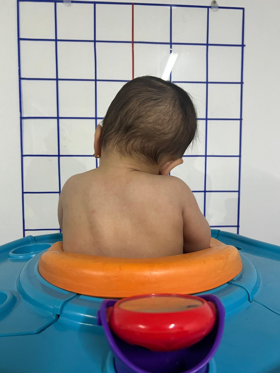 Eye-level view of physiotherapist gently stretching baby’s neck