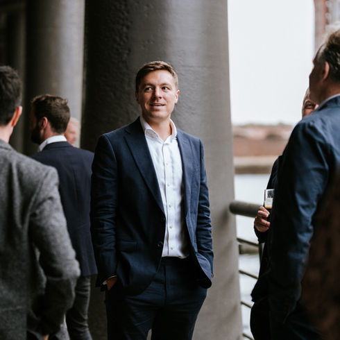 Man standing surrounding by people wearing a blue suit at a RICS Awards event in Liverpool