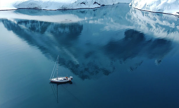 photographie d'un voilier devant un iceberg durant son exploration du Spitzberg