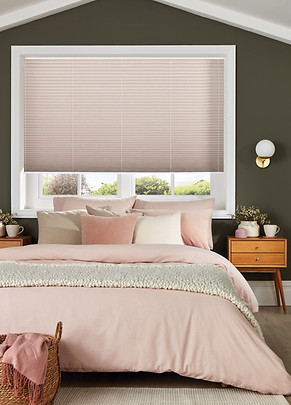 Pleated blinds in pink in a bedroom with pink bedding and green walls