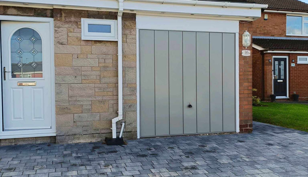 pebble grey up and over garage door on house with a front door. blue sky and clouds