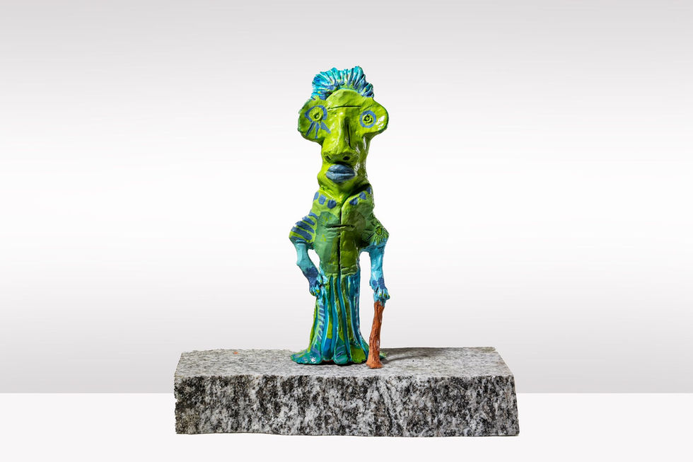 Colorful figurine art piece with green and blue colors, holding a staff.