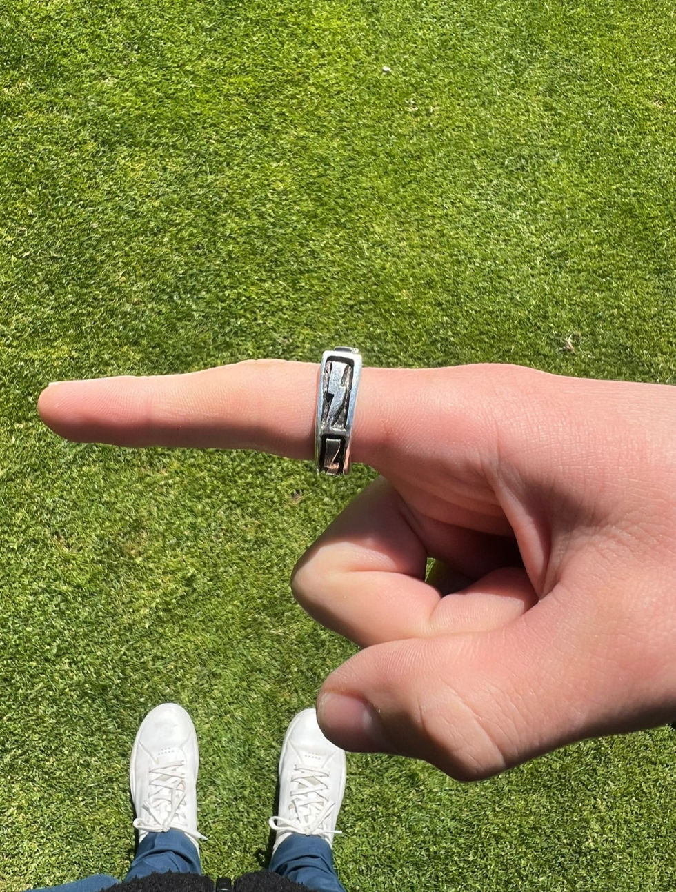 Hand with silver ring on finger, green grass background, Jewelry, rings visible