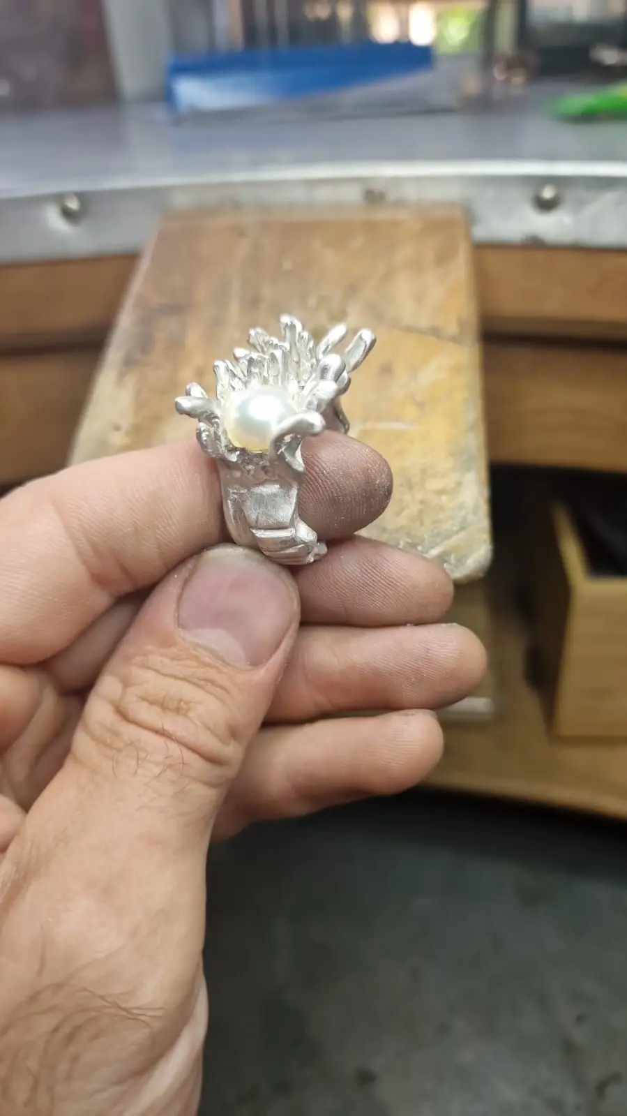 a person is holding a silver ring with a pearl in the center