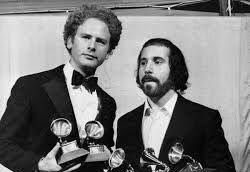 Art Garfunkel e Paul Simon posano fianco a fianco, tenendo i loro premi Grammy, con il palco dei 13th Grammy Awards 1971 a Los Angeles sullo sfondo.
