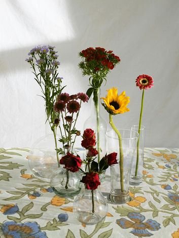 Block printed floral tablecloth with red and yellow flowers in vases placed on top.