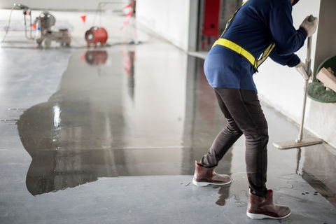 Construction worker painting epoxy flooring or floor hardener.jpg