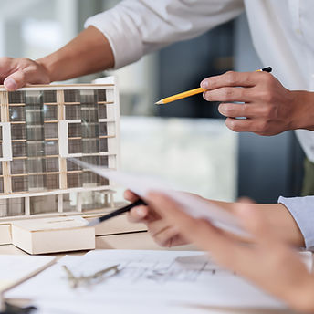 Two asian architect engineer inspecting building model and blueprint of drawing architectu