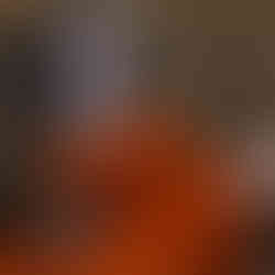 dark hair and blue eyed beautiful woman with tattoos, wearing an orange tulle dress poses confidently, leaning back and looking over her shoulder while casting a pious stare on the oregon coast